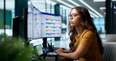 woman in front of three computer monitors